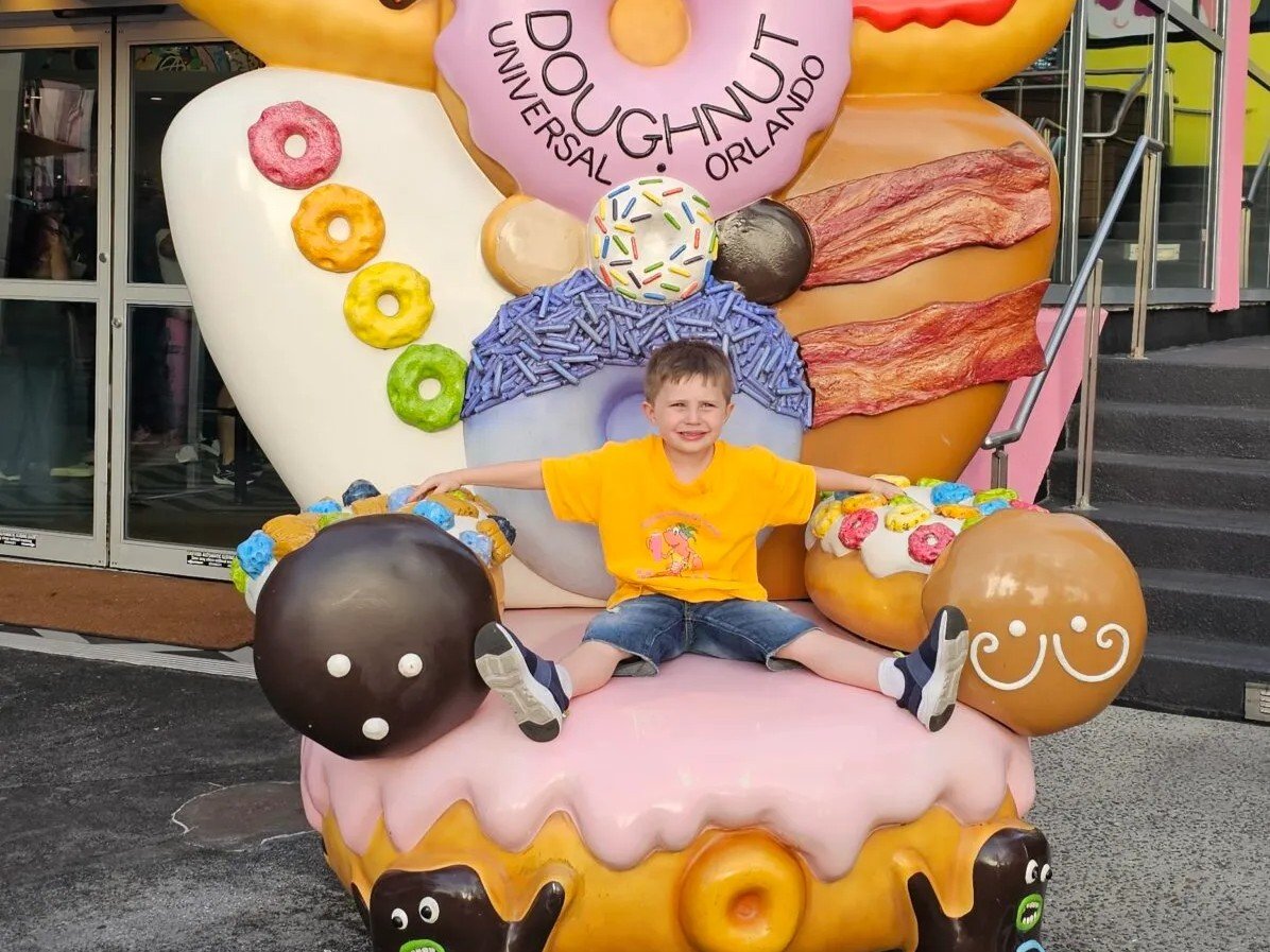 Colorful oversized donut and cupcake display outside a Doughnut Universal Orlando theme park attraction.