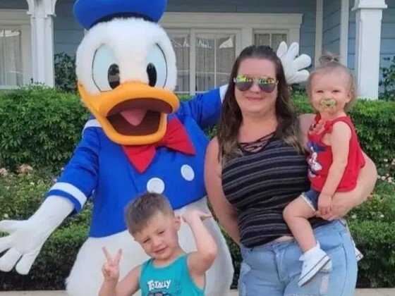 Colorful Disney family with Mickey Mouse mascot at an outdoor theme park attraction.